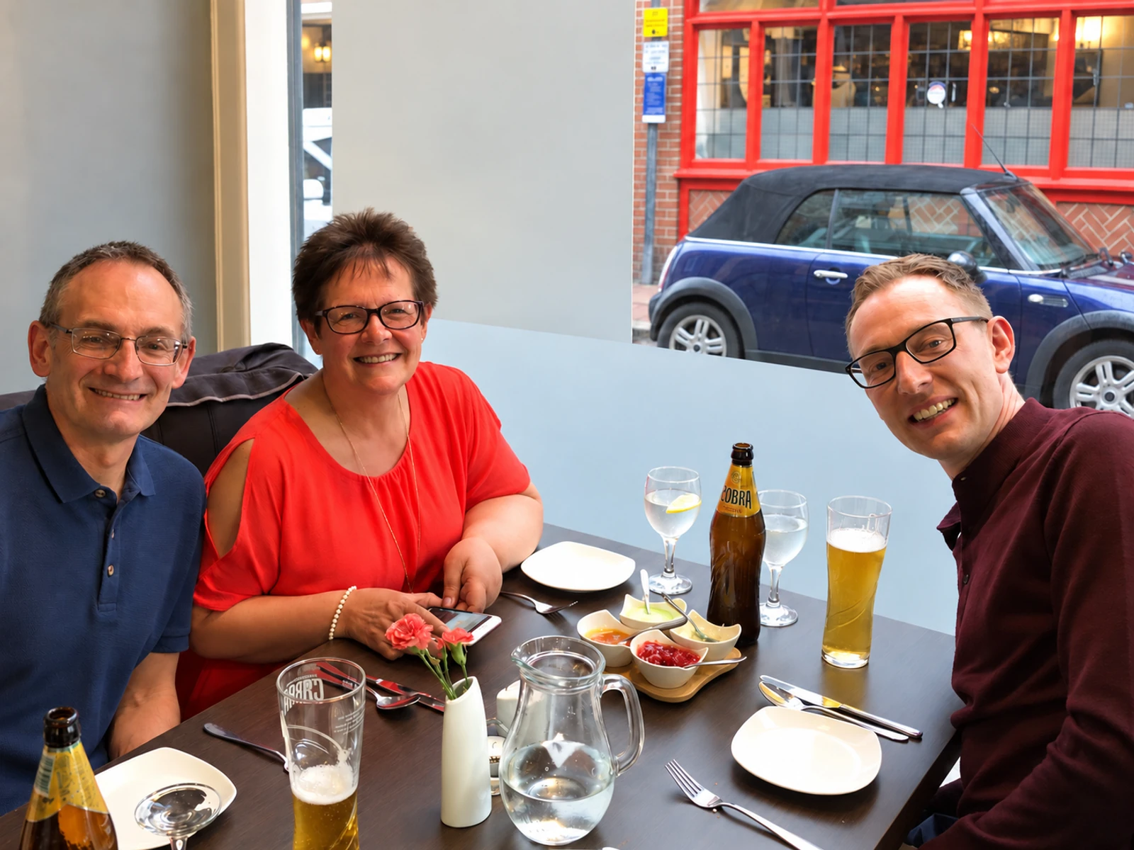 Three guests smiling over drinks at Masala Bay